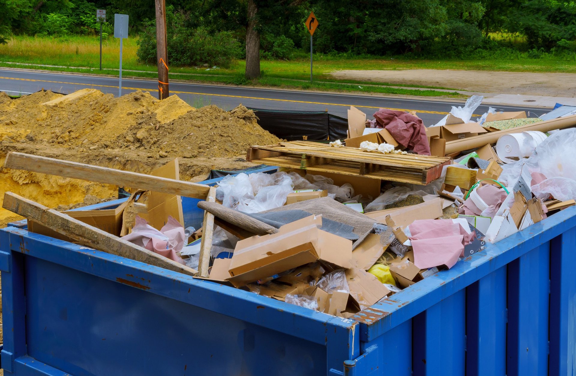 Industrial garbage bin blue construction debris container filled with rock and concrete rubble